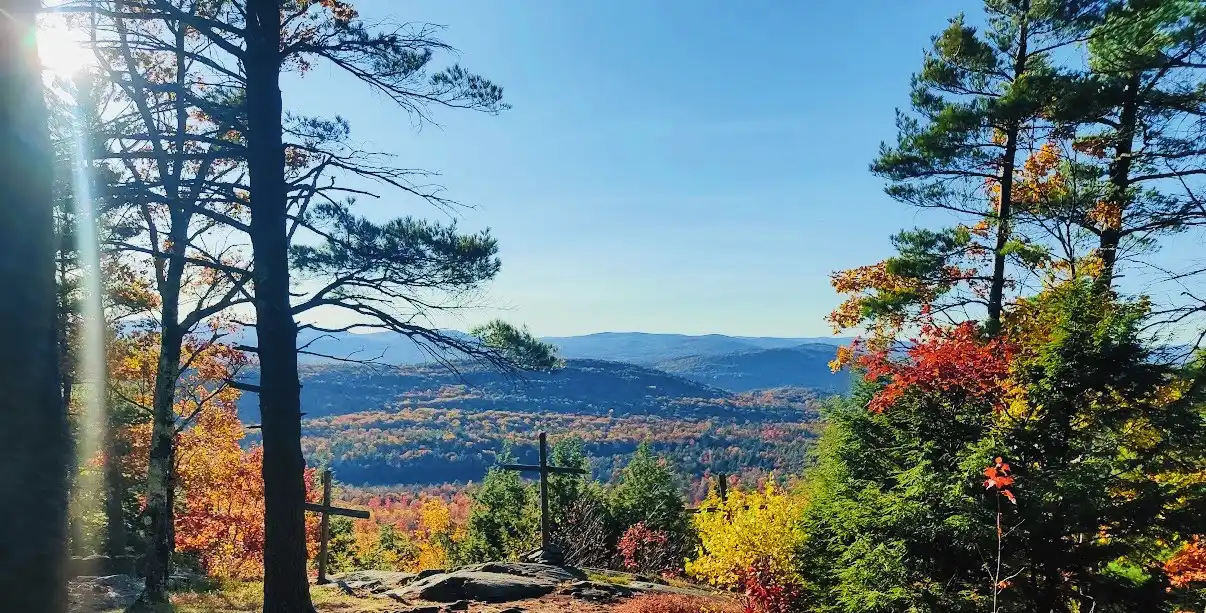 Wooden crosses on a rocky summit, pines framing an autumn valley and blue ridgelines