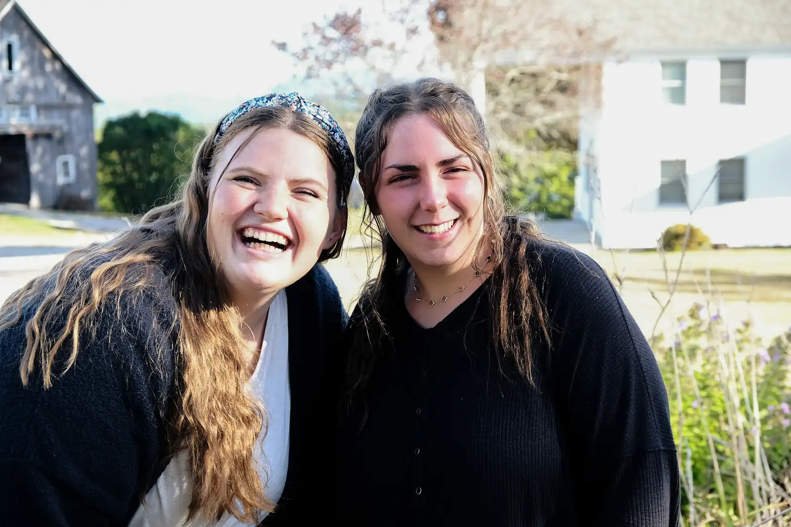 Two women smiling together outside a building on The Hill at His Mansion